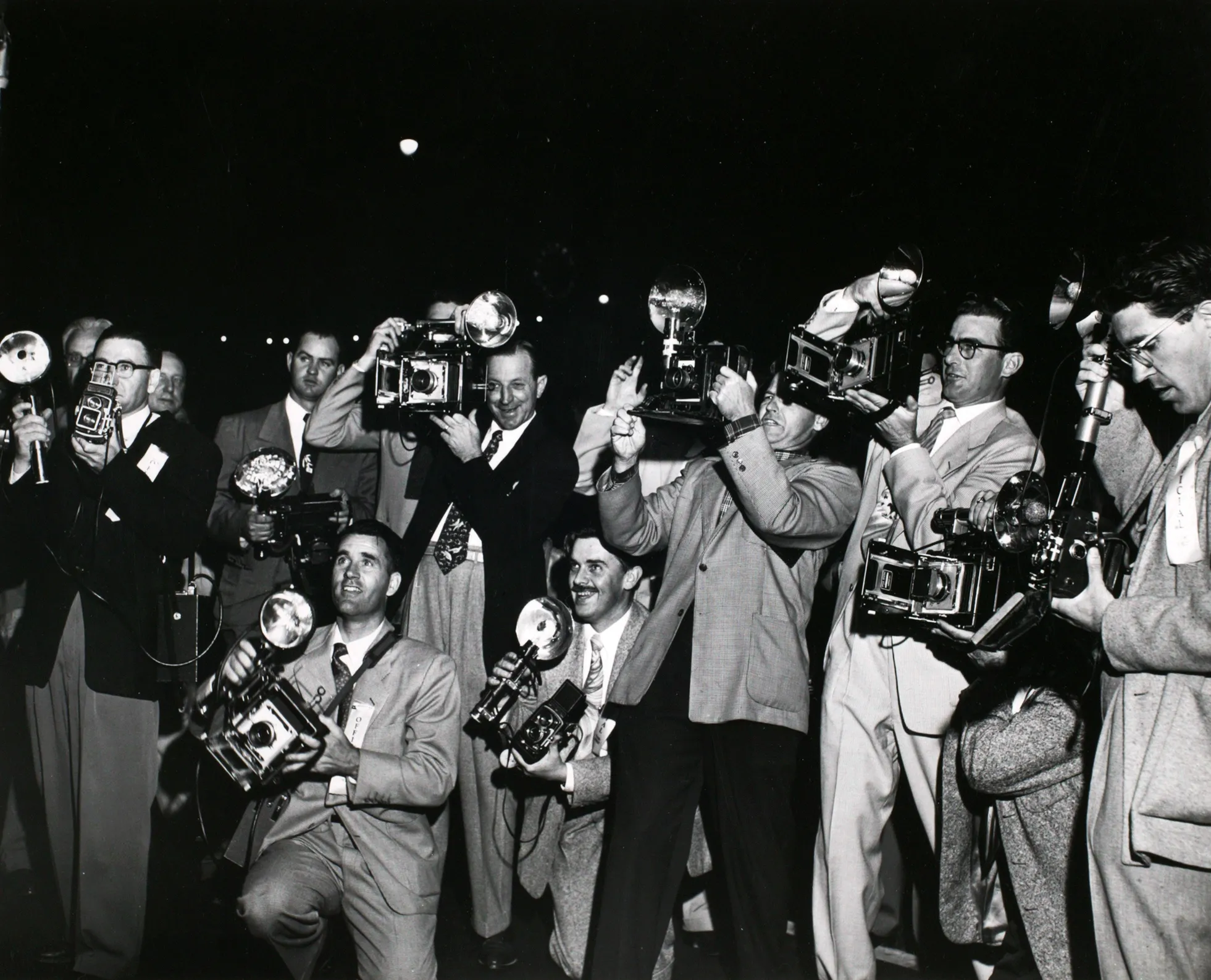 Black and white photograph of a group of photographers with their cameras at a premiere