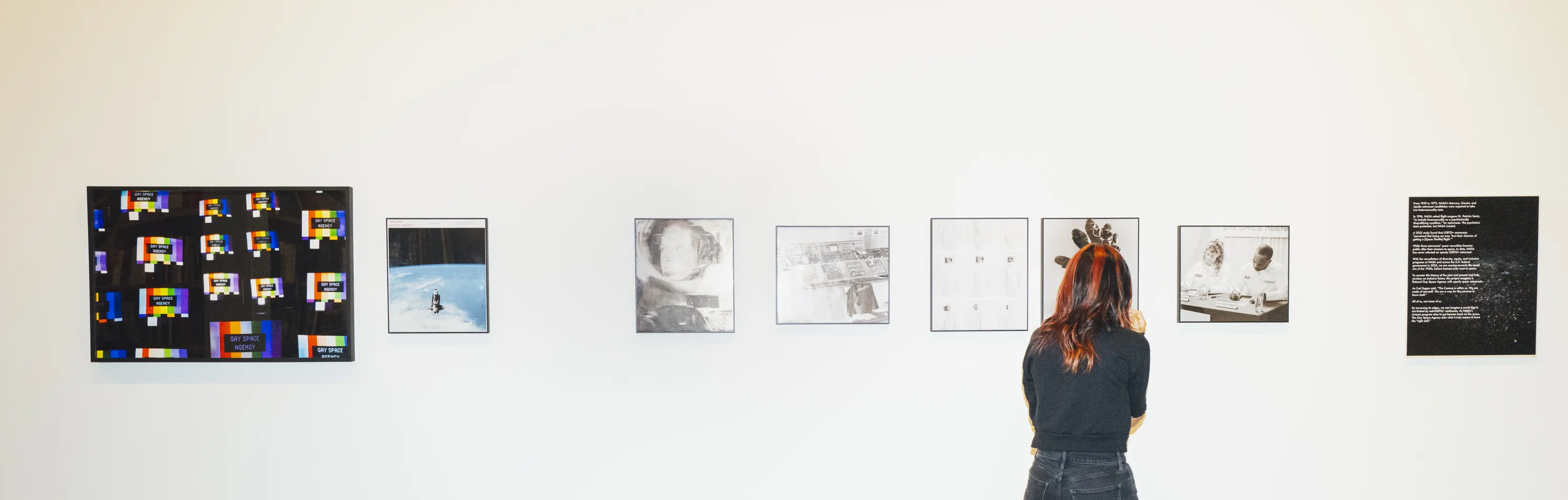 Person views framed photographs on wall